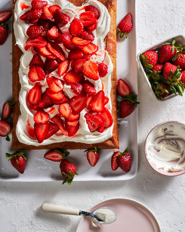 Un gâteau en feuille fraise-yuzu sur un plateau blanc, servi avec des fraises et un bol de glaçage.