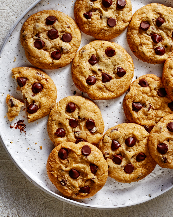 Des biscuits aux pépites de chocolat sur un petit plateau, avec un cookie partiellement mangé