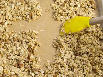 Le granola cru se faisant étaler sur une plaque à pâtisserie tapissée de papier parchemin