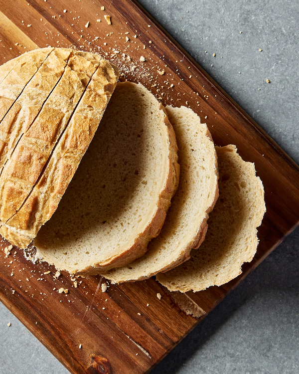 Un pain de levain sucré coupé en tranches sur une planche à découper en bois.