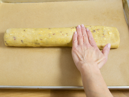 Une personne aplatissant un rouleau de pâte sur une plaque à pâtisserie