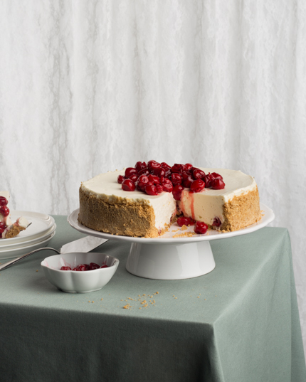 Un gâteau au fromage entier, une tranche en moins, sur un présentoir à gâteaux sur une table
