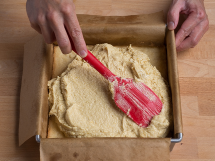 Frangipane non-cuite étendue dans son moule avec une spatule
