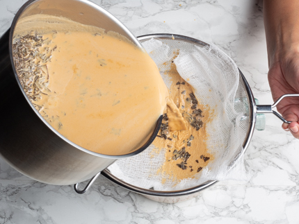 Verser le mélange de thé et lait évaporé à partir d’une casserole dans un tamis tapissé d’une étamine