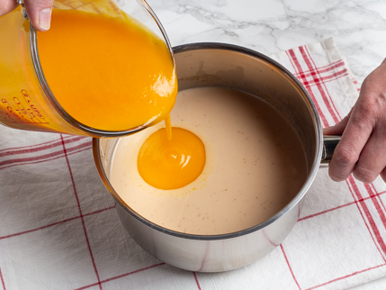 Verser la purée de mangue d’une tasse à mesurer dans une casserole de lait de coco et d’épices