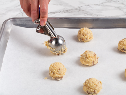 Déposer des boules de pâte sur une plaque à pâtisserie à l’aide d’une cuillère à crème glacée à gâchette