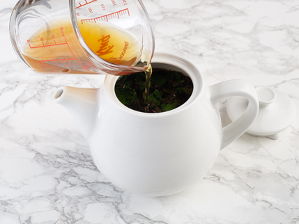 Liqueur de thé qui se fait verser d’une tasse à mesurer dans une théière