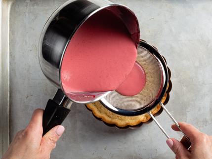 Verser la panna cotta framboises et eau de rose dans la croûte cuite en la filtrant au tamis
