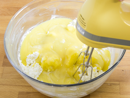 Le fromage cottage et le fromage à la crème recouvert du mélange de jaunes d'œufs dans un bol, avec un batteur électrique
