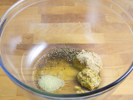 Sucre, moutarde, huile, sel et poivre dans un bol en verre