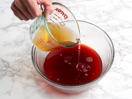 Verser le vinaigre de cidre de pomme à partir d’une tasse à mesurer dans un bol en verre qui contient du sirop simple