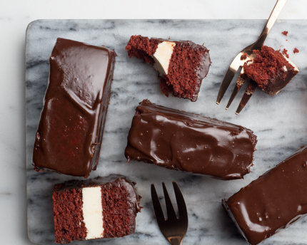 Gâteau red velvet trempé dans du chocolat avec des fourchettes sur une planche à découper