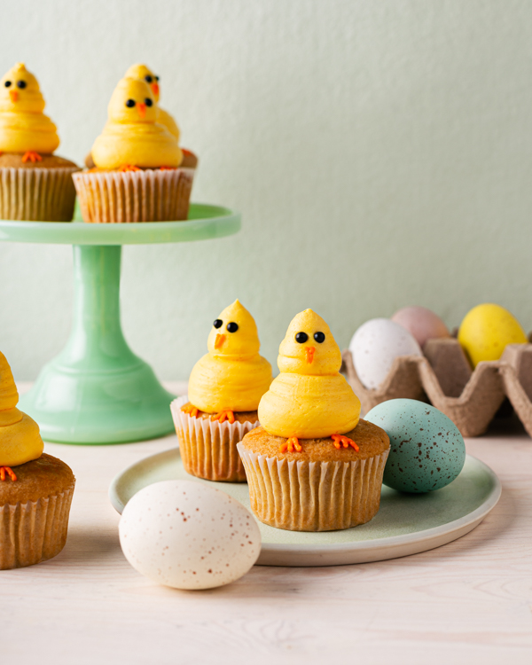 Cupcakes décorés avec des poussins jaunes sur un stand de gâteau avec des oeufs colorés