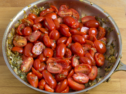 Un bol à mélanger rempli de tomates cerises coupées en deux avec assaisonnements