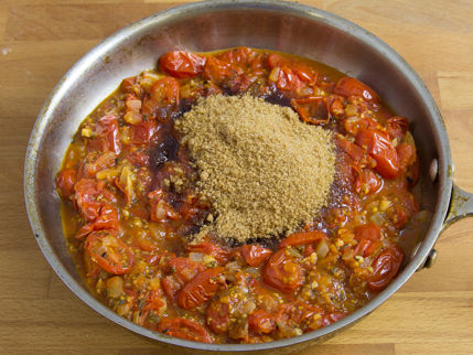 Un bol de tomates cerises cuites avec assaisonnements et la Cassonade de style Demerara sur le dessus