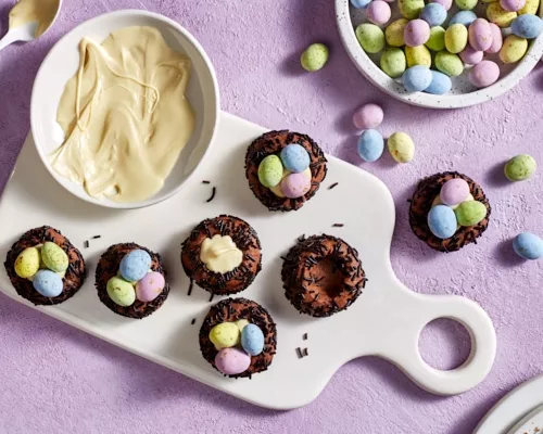 Sept biscuits au chocolat en forme de nid d'oiseau garnis de chocolat blanc et d'œufs en chocolat enrobés de bonbons