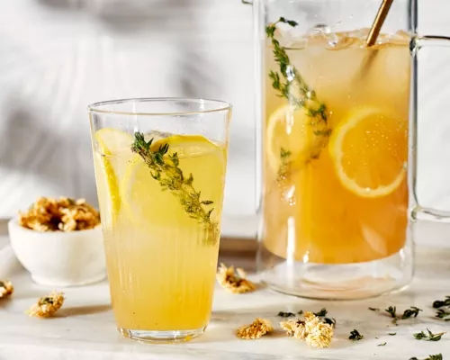 Limonade pétillante au thé de chrysanthème dans un verre servie avec des tranches de citron et fleurs de chrysanthème