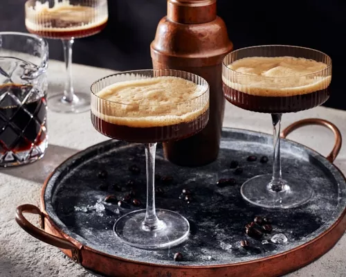 Deux verres de martini espresso sur un plateau avec un shaker à cocktail et un pichet en verre de martini