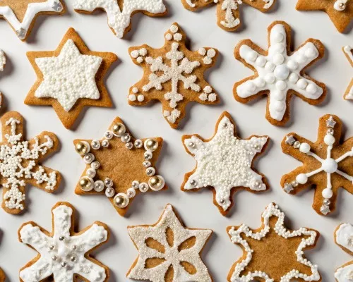 Biscuits au mélange à pain d’épices en forme d’étoiles et de flocons de neige, décorés de glaçage royal et de confettis