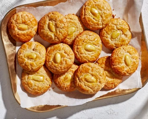 Une douzaine de biscuits dorés aux amandes sur un plateau en cuivre.
