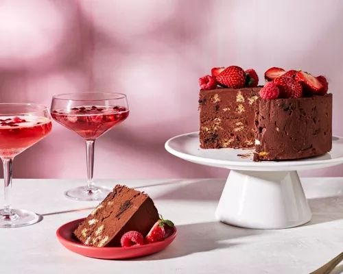 Un gâteau gaufrettes sans cuisson au chocolat épicé garni de fraises et de framboises sur un présentoir à gâteau blanc