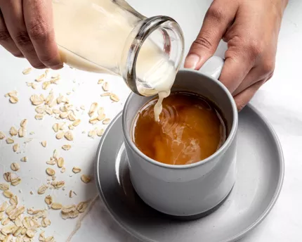  Verser de la boisson d’avoine à la vanille dans une tasse à café avec une bouteille de verre