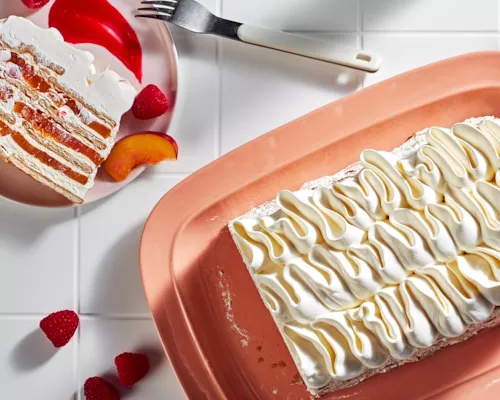 Gâteau glacé Peach melba vu de l'extrémité tranchée, révélant des couches de biscuits, de crème, de pêches et de framboises.