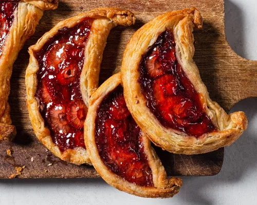 Quatre galettes aux fraises et aux dattes sur une planche à découper en bois