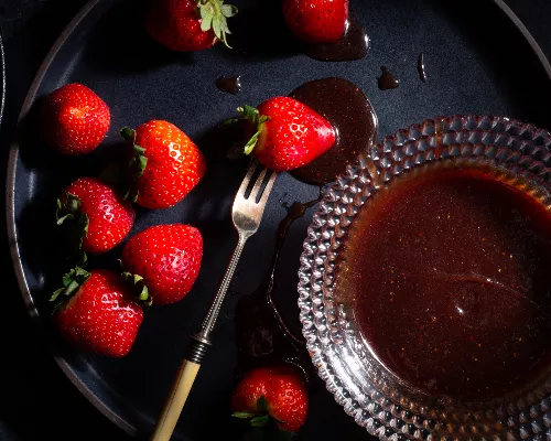 Bol en verre de sauce caramel aux fraises et au vin, avec des fraises entières