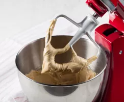 Glaçage au beurre noisette dans un bol à mélanger avec un batteur sur socle rouge