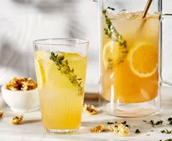 Limonade pétillante au thé de chrysanthème dans un verre servie avec des tranches de citron et fleurs de chrysanthème