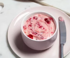 Un bol rose de fromage à la crème aux canneberges rôties, sur une assiette et avec un couteau