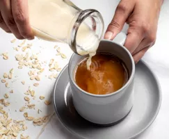  Verser de la boisson d’avoine à la vanille dans une tasse à café avec une bouteille de verre