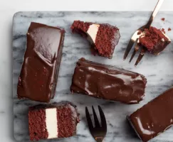 Gâteau red velvet trempé dans du chocolat avec des fourchettes sur une planche à découper