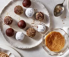 Boules de bourbon épicées sur un plateau, garnies de sucre glace, de noix concassées et de sucre turbinado