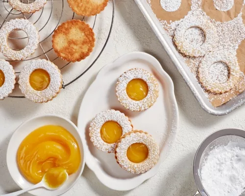Biscuits au curd d'agrumes sur un plateau avec des biscuits non finis sur une grille de refroidissement